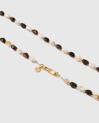 Macro close-up of the polished tortoiseshell resin beads and gold-plated clasp, each strap assembled by hand