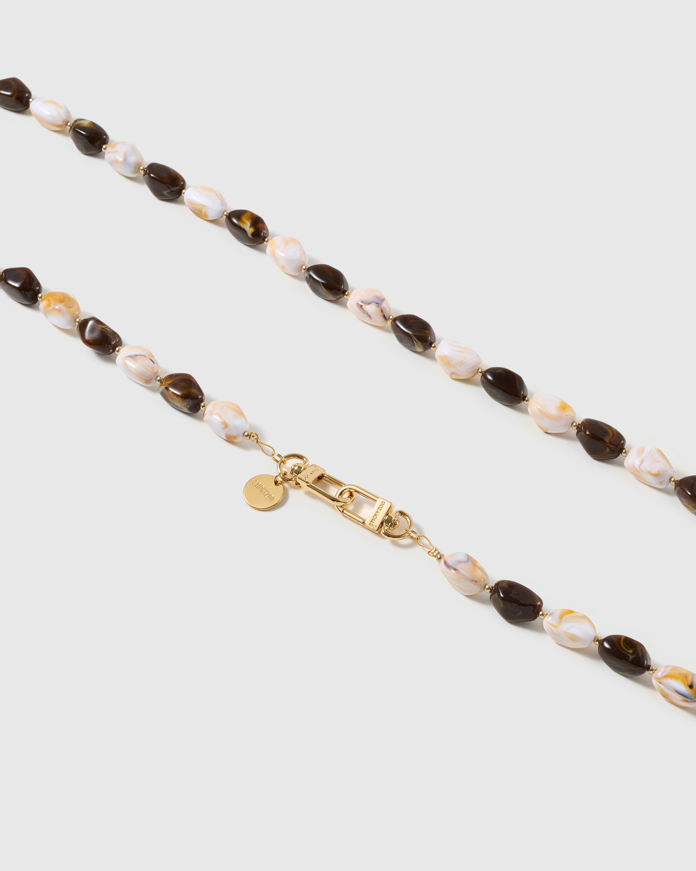 Macro close-up of the polished tortoiseshell resin beads and gold-plated clasp, each strap assembled by hand