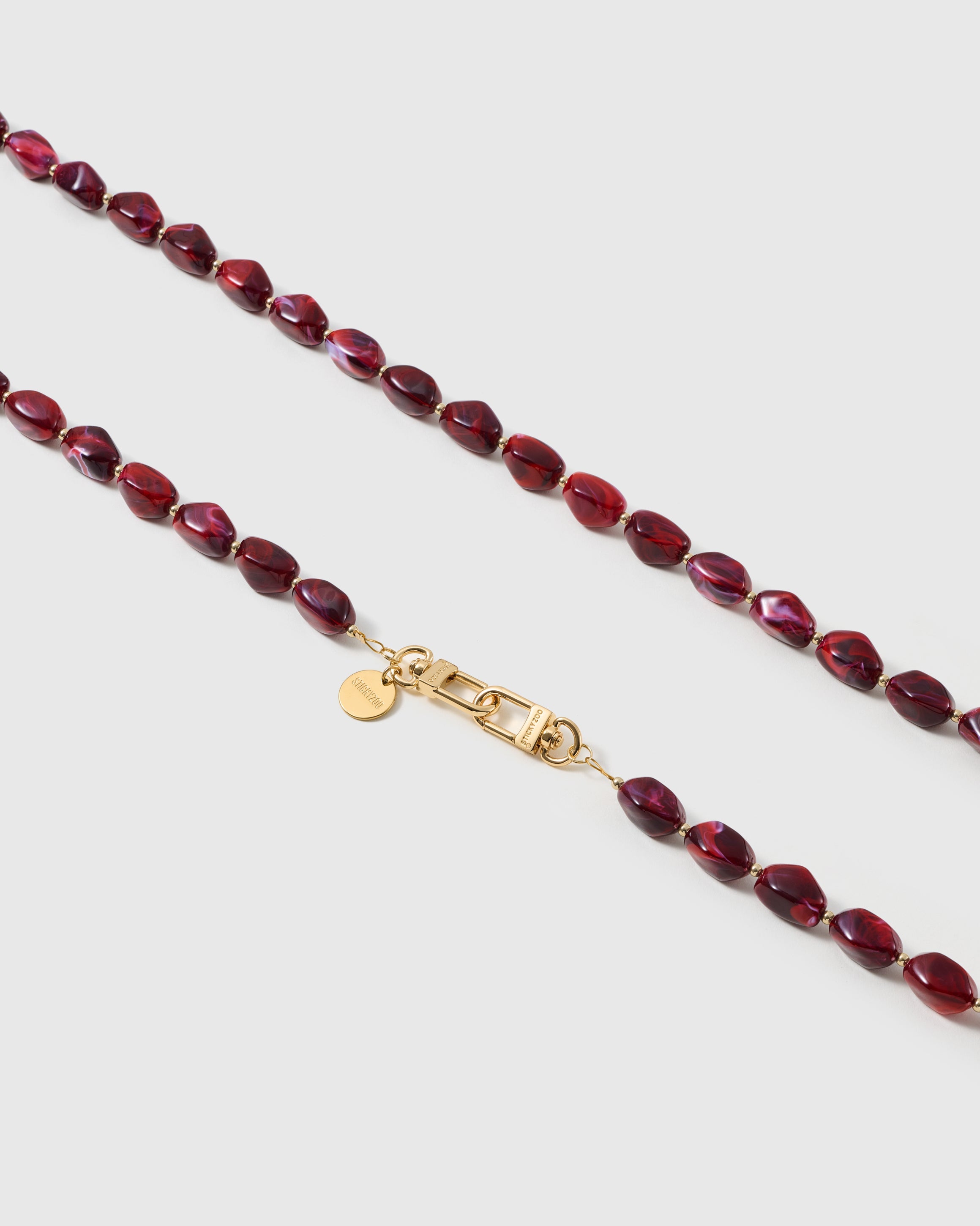Macro close-up of the polished garnet resin beads and gold-plated clasp, each strap assembled by hand