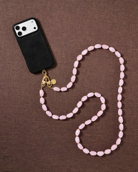 Petal-pink beaded cross-body phone strap styled on fabric, handmade not factory