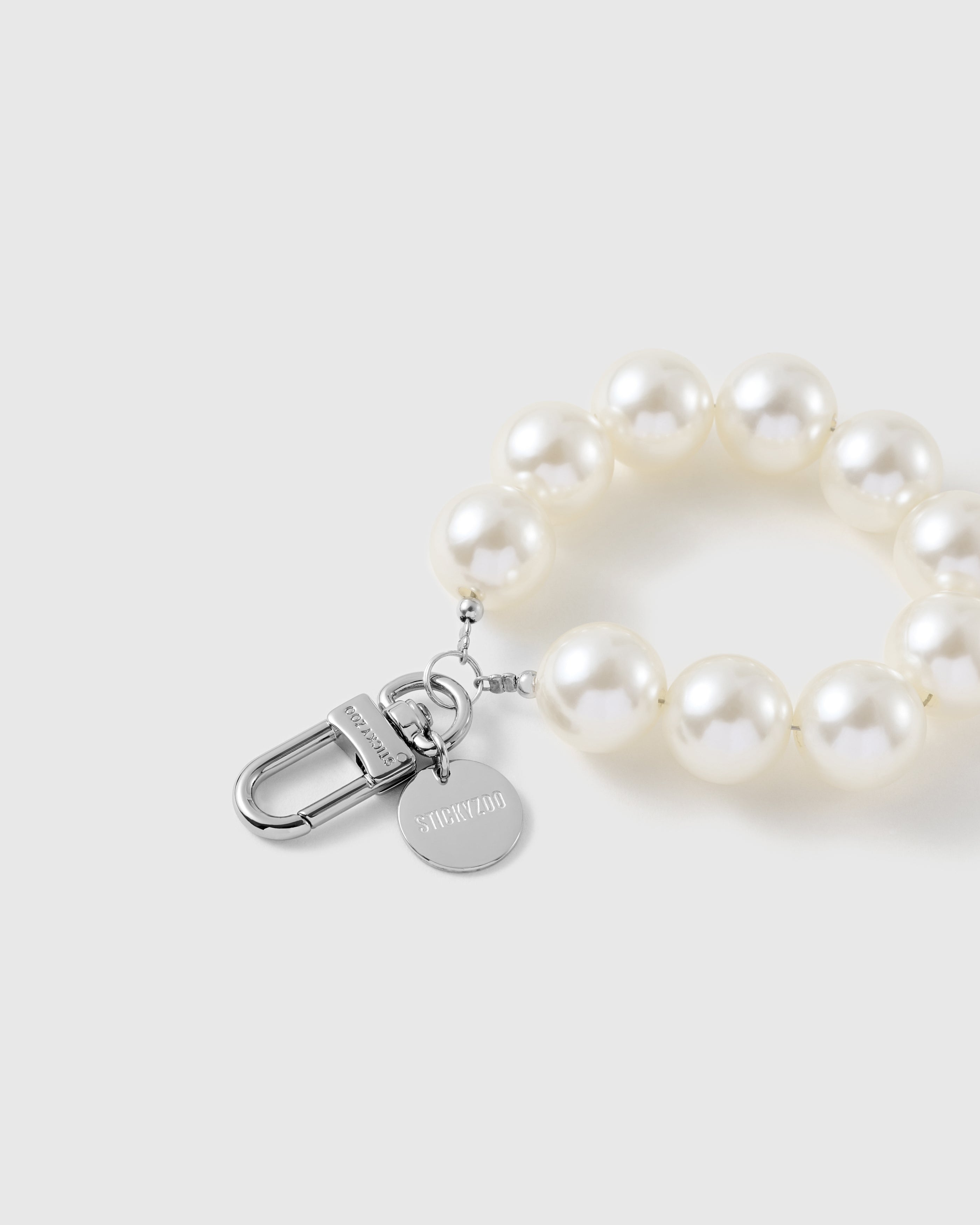 Close-up of the silver-tone hook, engraved STICKYZOO disc and white pearl-style beads — clean even sheen