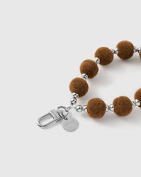 Hazelnut velvet pom strap attached to a phone case with the included Phone Strap Card