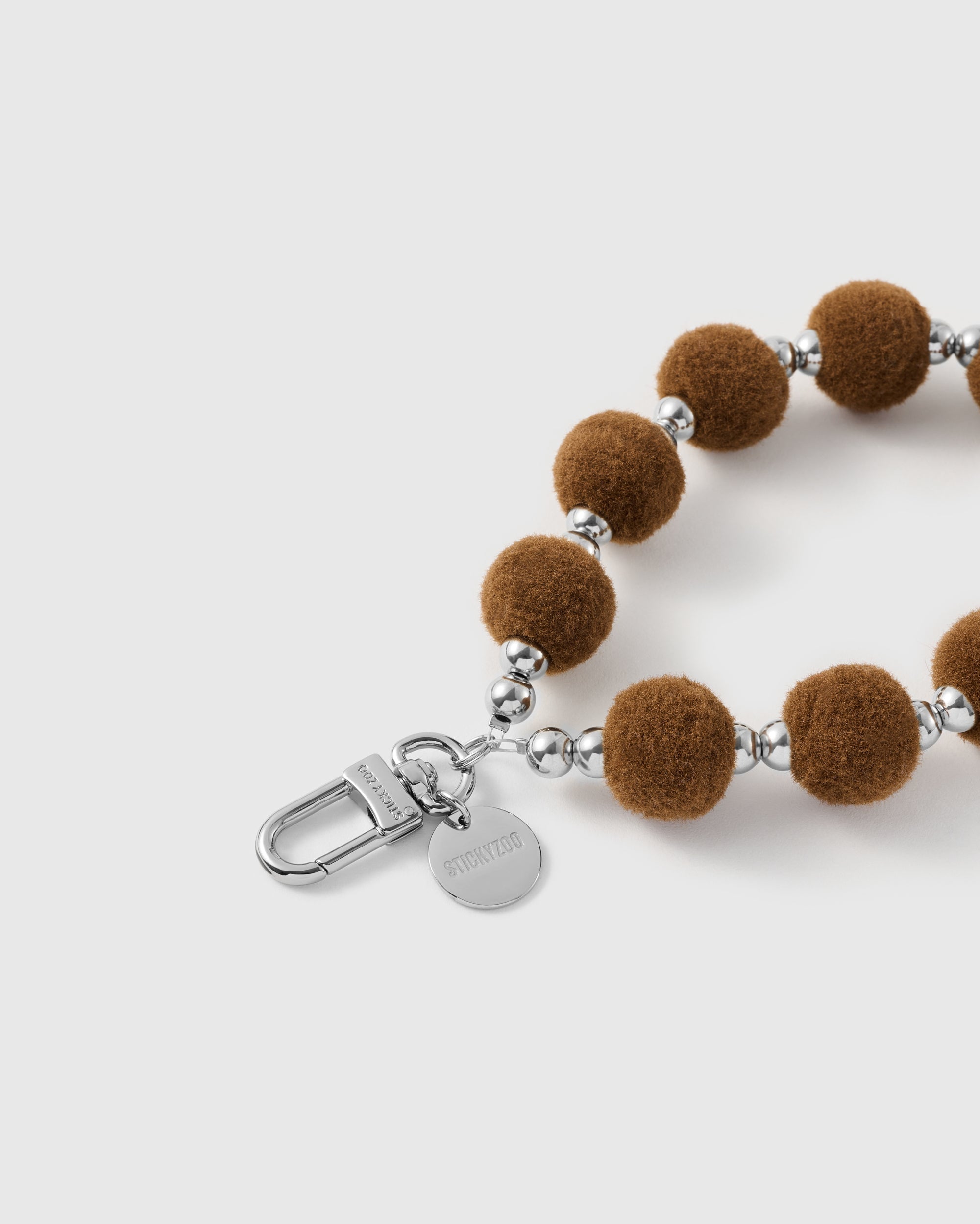 Hazelnut velvet pom strap attached to a phone case with the included Phone Strap Card