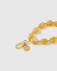 Close-up of the 18K gold-plated hook, engraved STICKYZOO disc and amber marbled beads — no two alike