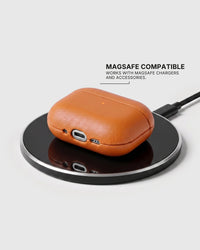 Orange AirPods case on a wireless charging pad with text stating MagSafe compatibility