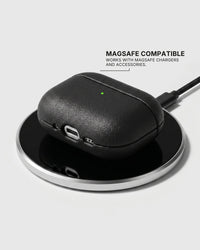 Black AirPods case on a wireless charging pad with text stating MagSafe compatibility