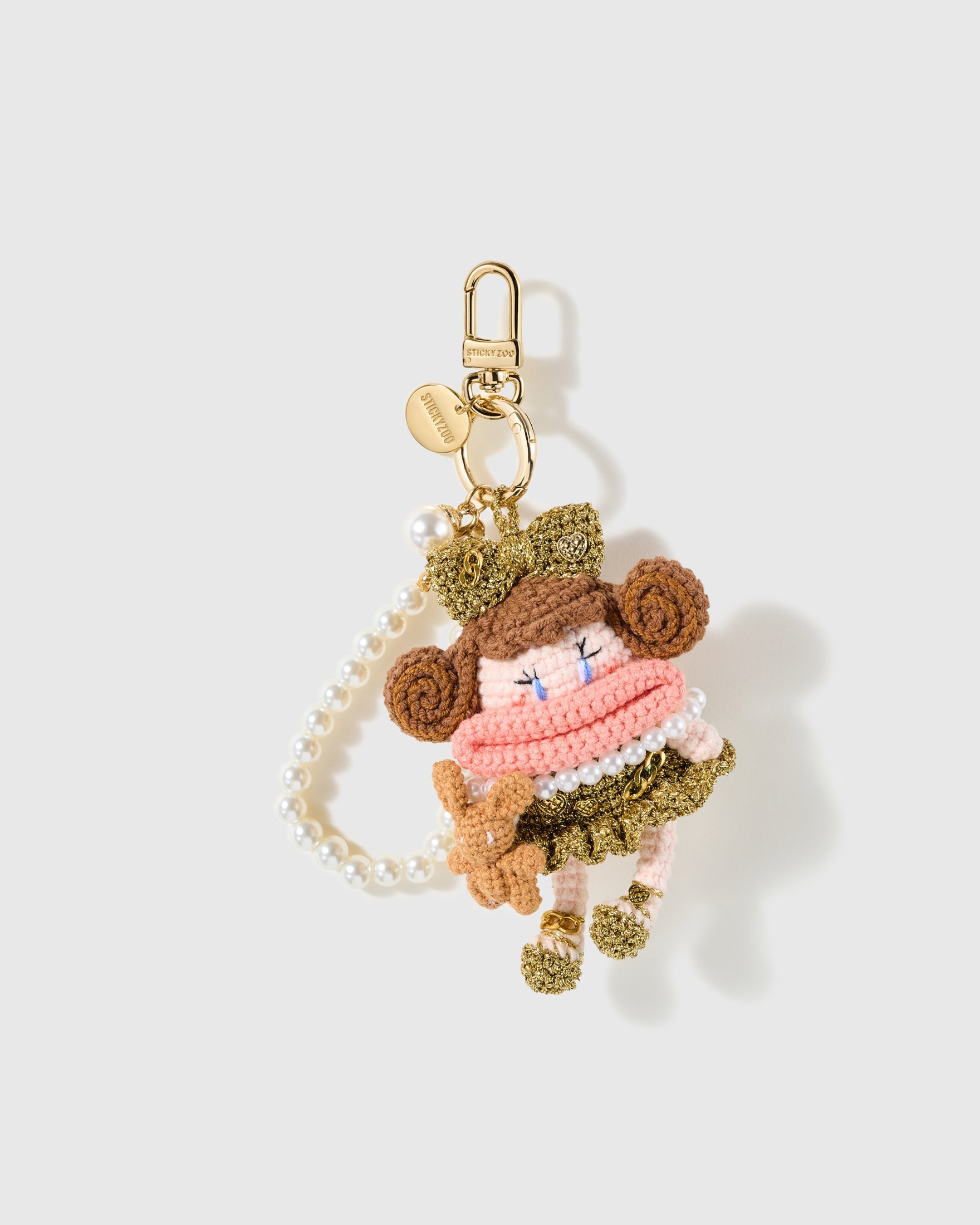 Pearl Loop Dress-Up Bear Crochet Charm with a pink-and-olive outfit, curled side details and pearl-look loop make the composition feel layered on a light background