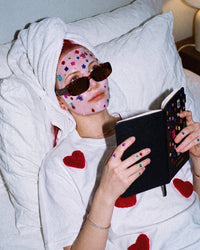 Person journaling with the open Gemstone Notebook and its raised multicolored cover details visible